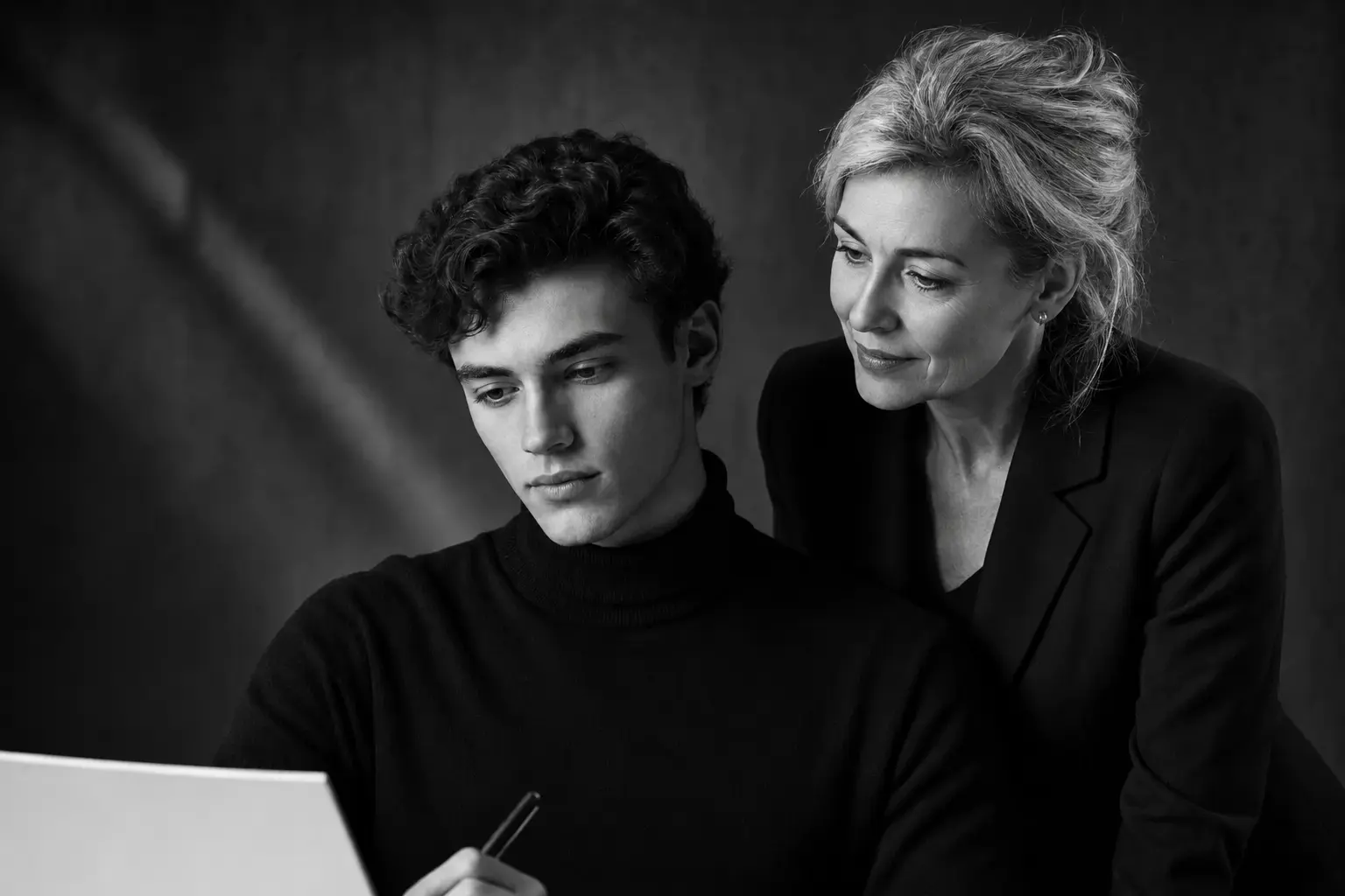 Un étudiant et une professeure élégante travaillent ensemble devant un ordinateur